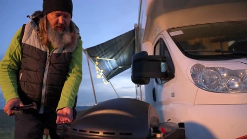 Man Grilling Chicken by RV in Rural Setting