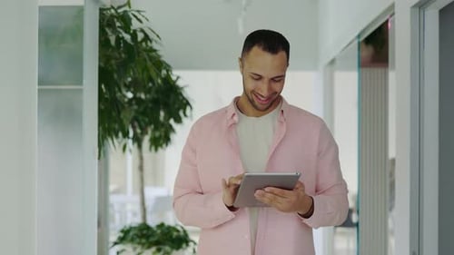 Positive Male Manager Walking in the Office Working on Digital Tablet Successful Manager Using