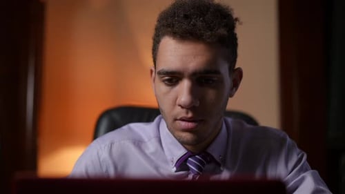 A Focused and Ambitious Young Man Diligently Working on His Laptop in a Professional Setting
