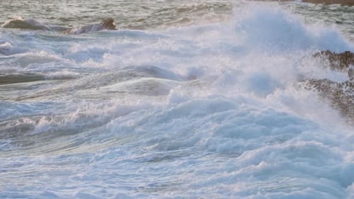 Sunset Glistens on Ocean Waves Crash Against Jagged Rocks Foam Sprays Coastal Nature Scene Filmed at