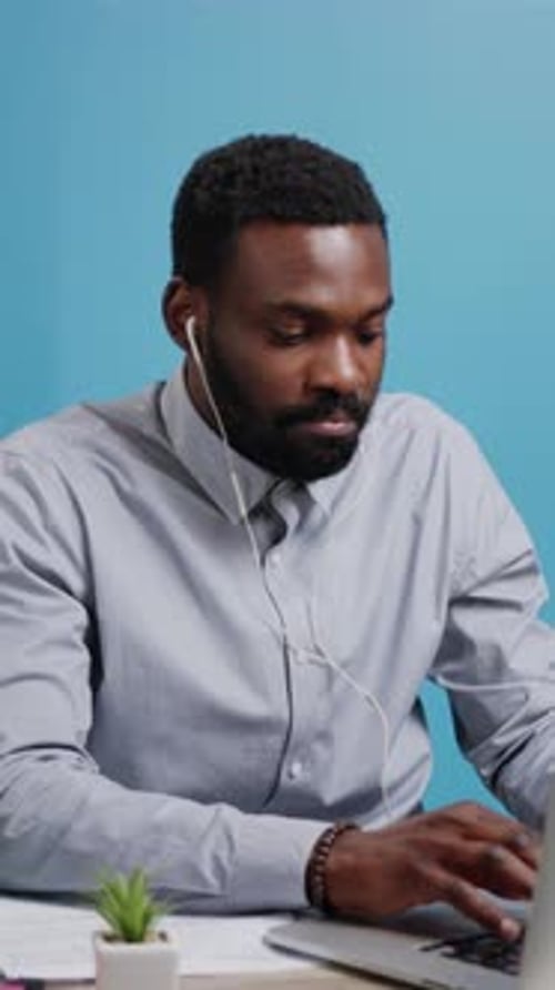 Man Working on Laptop with Headphones at Desk