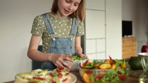 Girl Assembling Sandwiches with Salad Greens in Kitchen