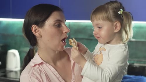 Mother and Daughter Sharing Pizza in Kitchen