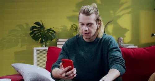 Man Cheering While Looking at Phone on Sofa