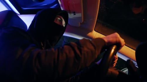 Masked Person Driving Car at Night in City