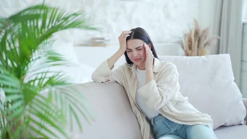 Brunette Woman Cries on a Sofa in Apartment
