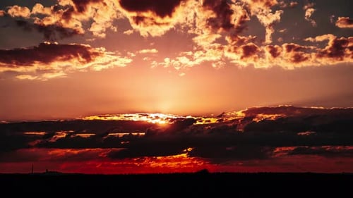 Zeitraffer des Dramatisch Sonnenuntergangs am orangefarbenen Himmel durch geschichtete Wolken