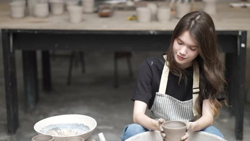 Young women is making earthenware at workshop.