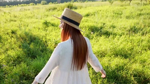 Woman in White Dress Enjoys Sunny Meadow Walk