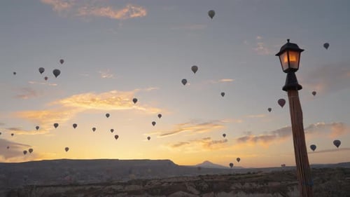 A vast number of hot air balloons in Cappadocia, with the sun about to rise behind the mountains.