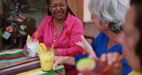 Multiracial Senior Women Drinking Smoothies Together at Bar Outdoor 60s