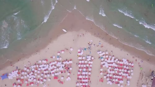 Tropical beach with colourful umbrellas and people enjoying the calm water