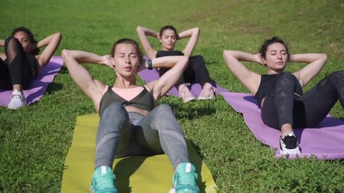 Women Doing Sit Ups on Yoga Mats in Park