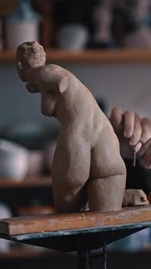 Skilled Potter Sculptor Carefully Working on a Clay Female Statue with Pottery Loop in Crafts Studio