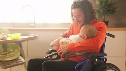 Smiling Man in Wheelchair Holding an Infant