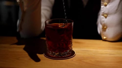 Bartender stirs sophisticated cocktail on warmly lit bar