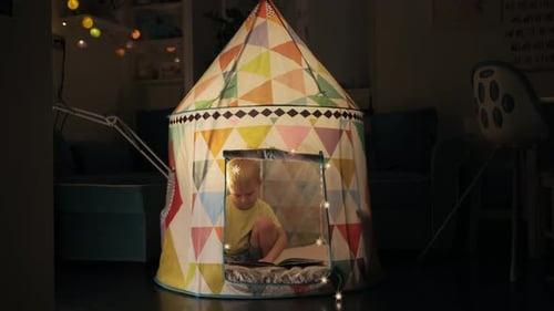 Young Child Reads in a Colorful Play Tent