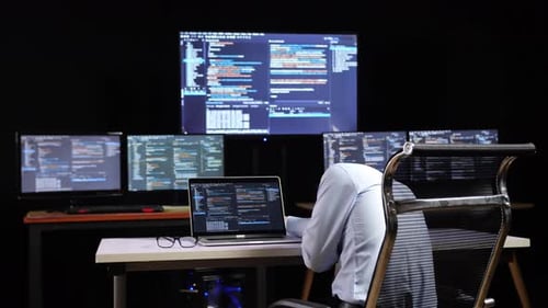 Programmeur endormi pendant l'écriture de code par un ordinateur portable utilisant plusieurs moniteurs affichant la base de données