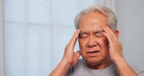 Asian old man with migraine headache. Elderly man suffering from a headache.