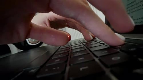 Eine Frau mit roten Nägeln tippt auf einem Laptop