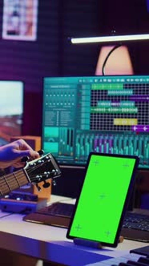Un ingeniero de audio y vídeo vertical practica la afinación de su guitarra acústica en un estudio doméstico