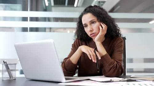 Young businesswoman is bored sitting at a work desk workplace in business office. Exhausted female