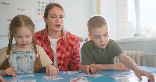 Teacher Guiding Young Children Through an Engaging Classroom Flashcard Activity at a Blue Table with