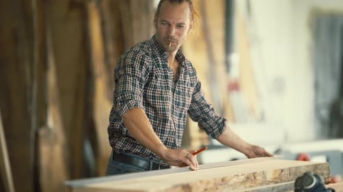 Schreiner misst Holzbrett in seiner Werkstatt