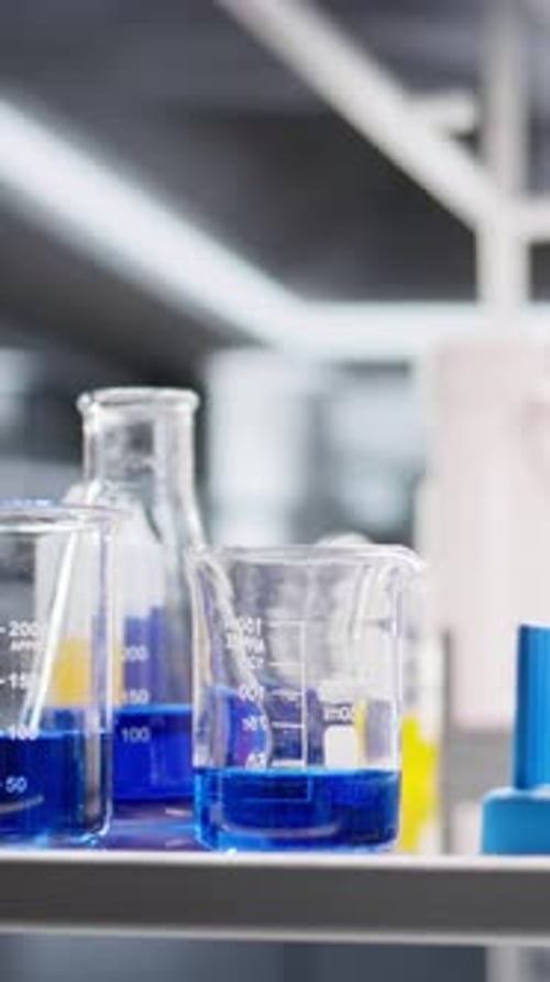 Laboratory beakers filled with blue liquid on shelf