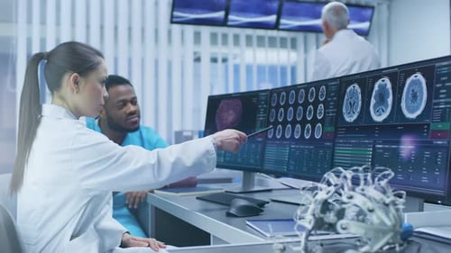 Medical Scientist and Surgeon Discussing CT Brain Scan Images on a Personal Computer in Laboratory.