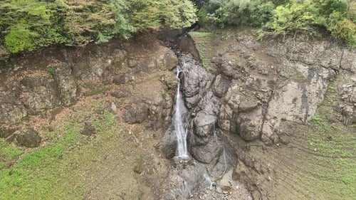 Scenic Waterfall Cascades Down Rocky Green Hillside
