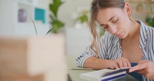 Young Woman Reading a Book Indoors at Table
