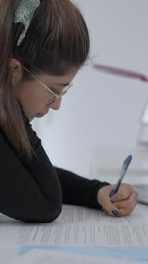 A Young Student of Colombian Universitary Sitting at a Table and Writing in Her Paper Girl Studying