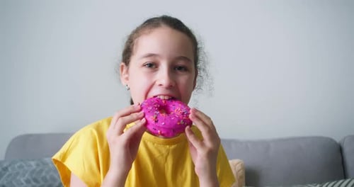 Portrait of a Happy Child Eating an Appetizing Sweet Donut with Glaze A Cheerful Caucasian Little