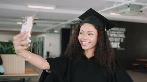 A Black teenage graduate student selfie with mobile phone in college.