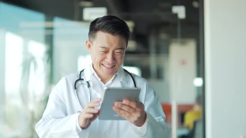 Asian male doctor advise patient remotely using digital tablet. Communicates online talks on video