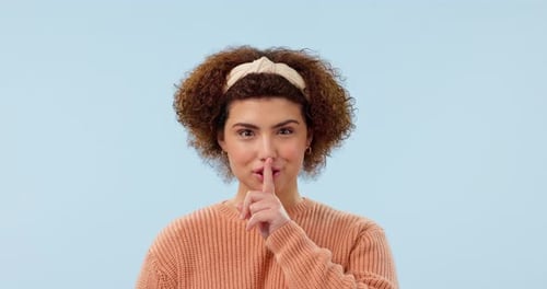 Woman with finger to lips, secret or privacy with confidential news in portrait on blue background