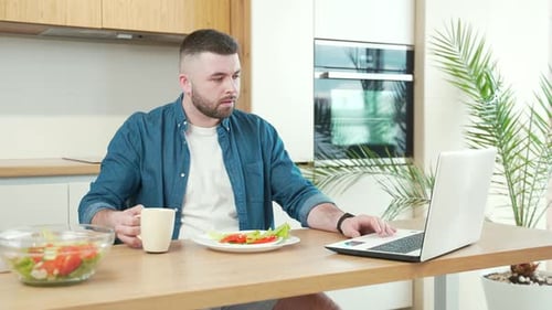 Young Adult Working on Laptop in Bright Kitchen
