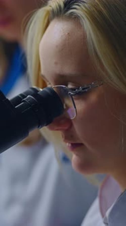 Woman Scientist Looking Through Microscope in Lab