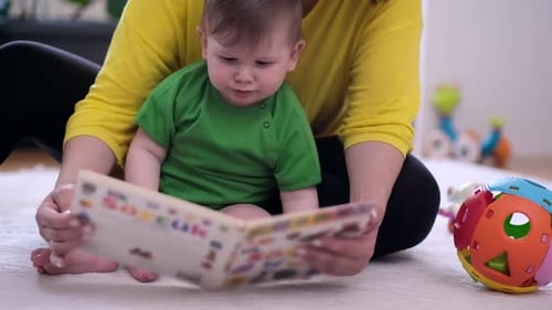 Baby and Adult Reading a Book Indoors