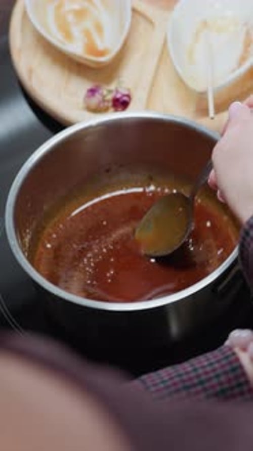 Partial View of Person Stirring Soup in Pot While Adjusting Position on Stove
