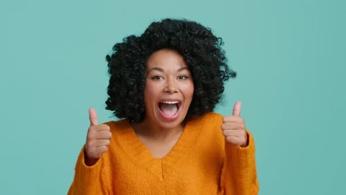 Woman Smiling Giving Thumbs Up on Blue Background
