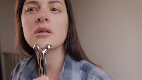 Young Woman Using Facial Massage Roller Indoors