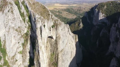 Flying through vertical limestone walls in a deep gorge, canyon, rock climbing aerial