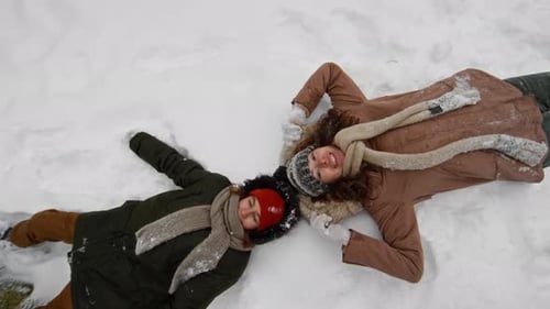 Portrait of Happy Young Mother and Son Falling in Snow during Winter Walk
