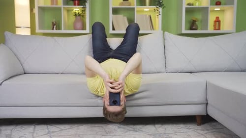 Teenager Lying Upside Down on Couch Using Smartphone