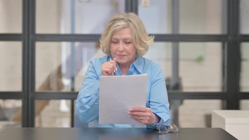 Senior Woman Reviews Documents with Surprised Expression