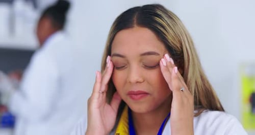 Young Woman Massaging Temples in Doctor's Office
