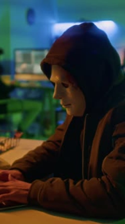 Masked Threat Actor Working on Laptop Causing Damage to Companys Reputation