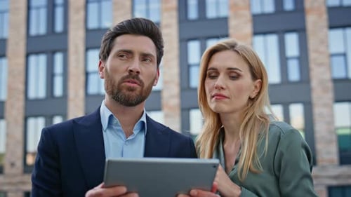 Business Partners Discussing Tablet Company Growth at Architecture Place Closeup
